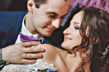 Wedding day. The bride and groom in a luxurious interior in lavender color. Wedding emotions. Beautiful bride and elegant groom at the ceremony.