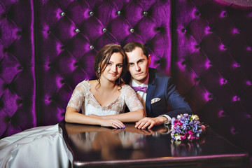Wedding day. The bride and groom in a luxurious interior in lavender color. Wedding emotions. Beautiful bride and elegant groom at the ceremony.