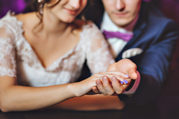 Wedding day. The bride and groom in a luxurious interior in lavender color. Wedding emotions. Beautiful bride and elegant groom at the ceremony.