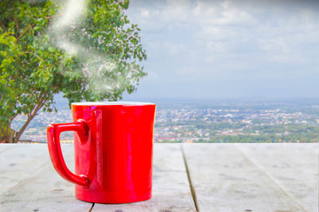Obraz premium hot coffee with white smoke in red cup on wood table