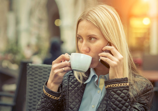 Woman seating in cafe with her phone and coffee.