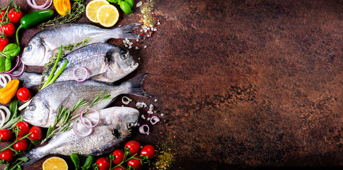 Fresh raw fish with lemon, herbs, onion, paprika, cherry tomatoes, onion, salt on rustic...