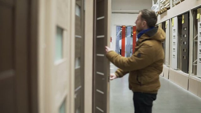 Man in hardware store chosing a door checking a lock