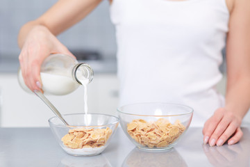 Female pouring milk in plate with oak flakes.