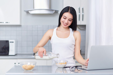 Brunette woman pouring milk in oak flakes.