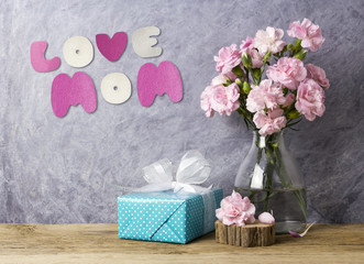 Mothers day concept of love mom letter pink carnation flowers in bottle and blue gift box on old wood