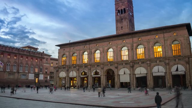 King Enzo palace at the main square of Bologna, Italy. Famous landmark at sunset at night. Time-lapse, tracking shot