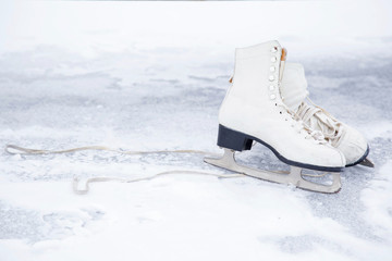 Old white skates on the ice area in winter day. Weekends activities outdoor in cold weather.