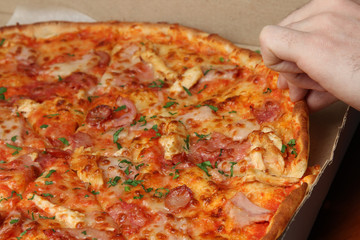  In the hand a slice of pizza. Closeup.