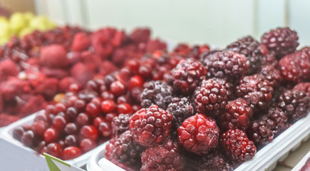 Close-up of frozen fruit in supermarket. Blackberry in focus, blurred Raspberrie