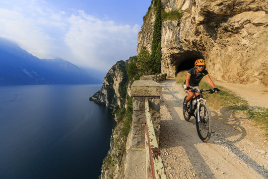 Mountain biking sunrise woman at sunrise over Lake Garda on path