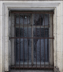 old window with metal grille on an abandoned building