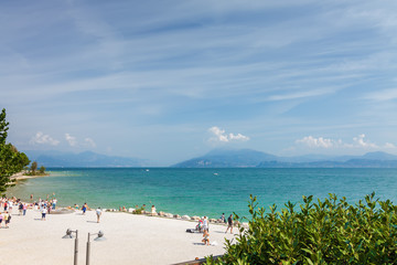 Sunny view of sand beach in Sirmione at Garda lake, Lombardia region, Italy.