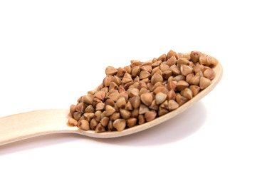 Uncooked buckwheat on wooden spoon. premium buckwheat groats on white background