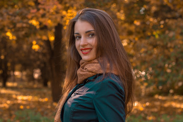 beautiful girl with red lipstick on lips stands in the Park by turning her head to the camera and smiling