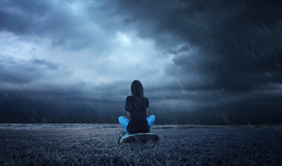 a lonely girl sitting on a wood in a rainy weather. - 136155247