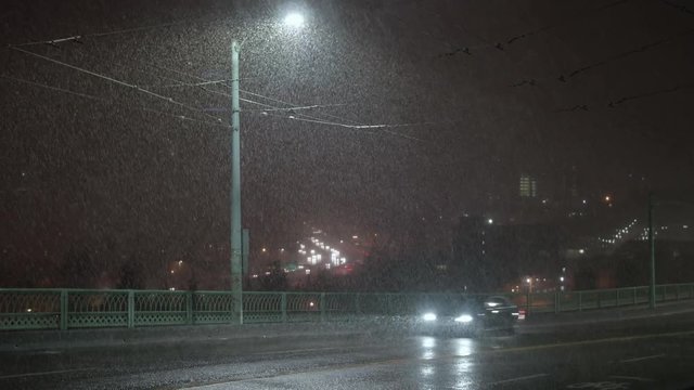 Dumping Snow with Cars Driving on City Streets at Night and Freeway Traffic in Background