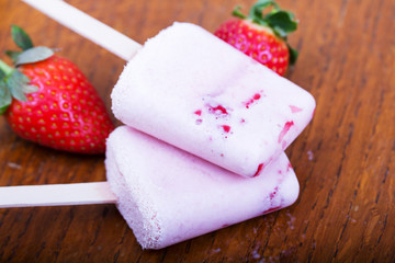 Homemade strawberry ice lolly on rustic background