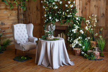 spring arbor, overgrown with greenery. A cozy corner with a soft arm-chair, a table, candles. Rustic style. Wooden interior with greenery