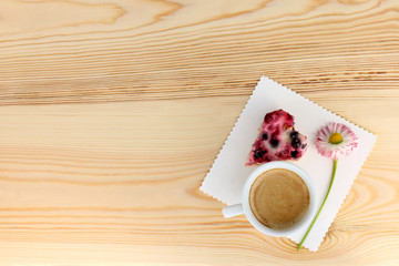 morning surprise for beloved/ frothy coffee with berry Cake in the shape of a heart and a flower on a light wooden surface