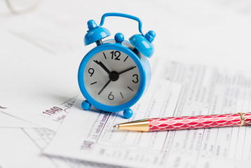 Alarm clock, pen and tax forms