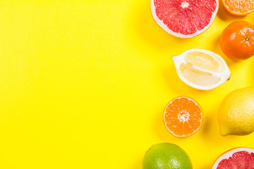 Several kinds of whole and cut citrus on a yellow background