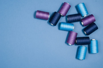 Top view of colorful thread spools over blue seamless background. Image taken from above.