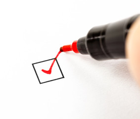 Hand with red pen marking a checkbox