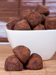 Black chocolate truffles in a white bowl covered with cinnamon powder