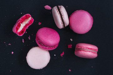 Macaroons on dark background, colorful french cookies macarons. The broken macarons with crumbs. Gidt for 8 March - International Women's Day
