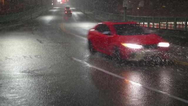 Pan Down to Cars Driving at Night in Dangerous Bad Weather with Thick Snow Flakes