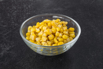 Canned corn in glass bowl for salad on the table in the kitchen. Healthy eating and lifestyle.