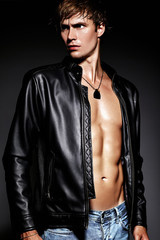 Young handsome muscled fit male model man posing in studio showing his abdominal muscles in ...