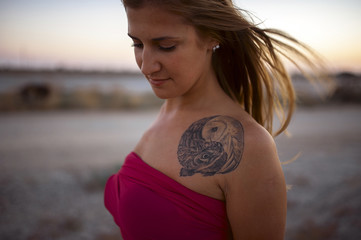 girl with a tattoo at sunset. hair flying