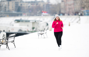 Girl wearing sportswear and running on snow during winter