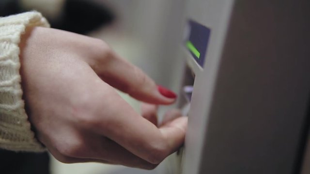 Woman's hand with painted red nails inserting credit card to ATM. Beautiful manicure