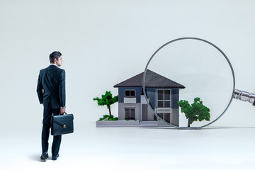 businessman and magnifying glass in front of house