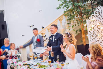 Newlyweds get an original gift butterfly from mother. Shocked and smiling bride. Groom emotions.