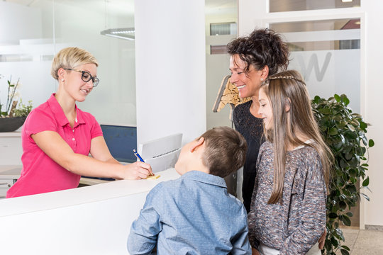 Mutter und Kinder bekommen eine Notiz von Zahnarzthelferin