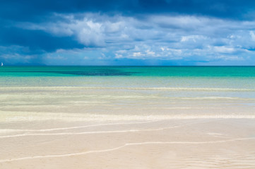 Obraz premium Rain clouds over the sea and white-sand beach with clear water