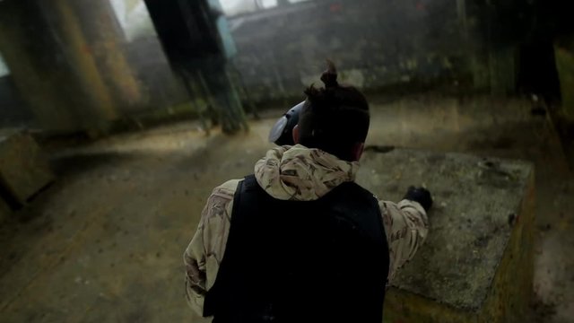 POV shot of Paintball player in protective uniform and mask aiming gun before shooting. Player gets shot. Violance and war concept.