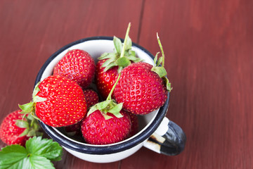 Fresh strawberry in a mug on the wooden brown table