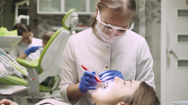Dentist check up girl's teeth, doctor teaches a child to brush teeth on a background. 4k footage. Dental clinic. Close-up.
