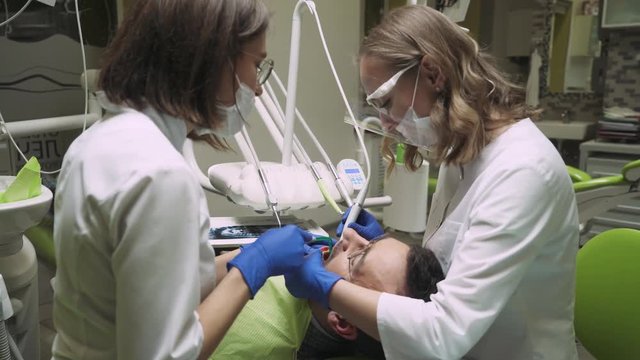 Dentists produce teeth cleaning man. 4k footage. Dental clinic. Close-up.