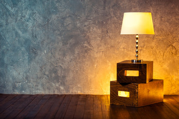 Floor retro lamp on two boxes in the room with a wooden floor and grunge texture wall