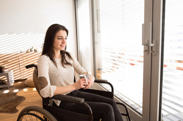 Beautiful young disabled woman in wheelchair at home.
