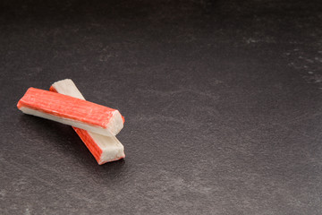 Crab sticks on the dark table in the kitchen. Healthy eating and lifestyle.