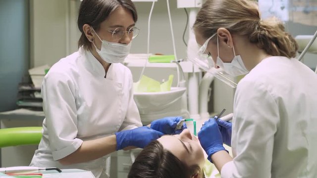 Dentists produce teeth cleaning girl. 4k footage. Dental clinic. Close-up.
