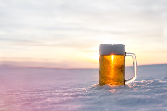 Mug of cold beer on the snow. Close up view.