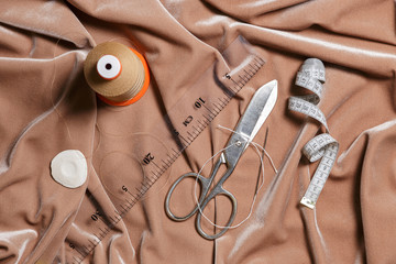 Sewing accessories on a beige fabric background. Top view.